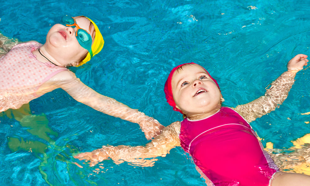 Bambini felici in piscina durante il corso di acquaticità