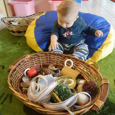 Bimbi che esplorano oggetti naturali dentro un cesto di vimini